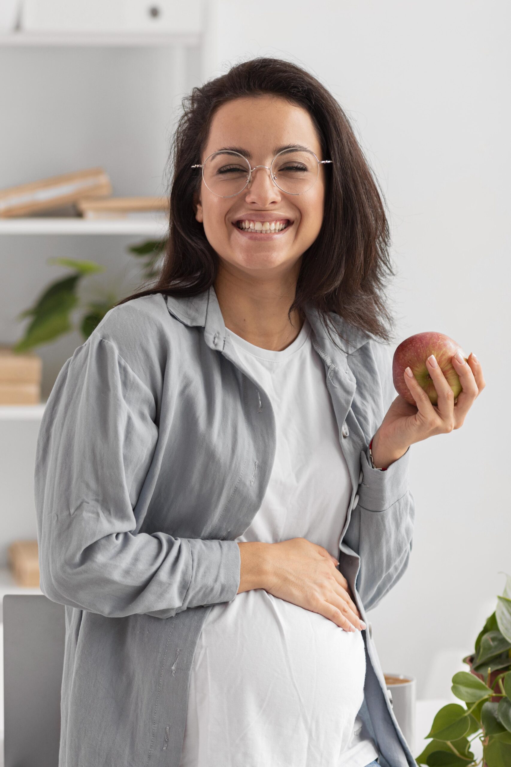 smiley-pregnant-woman-holding-apple-while-home